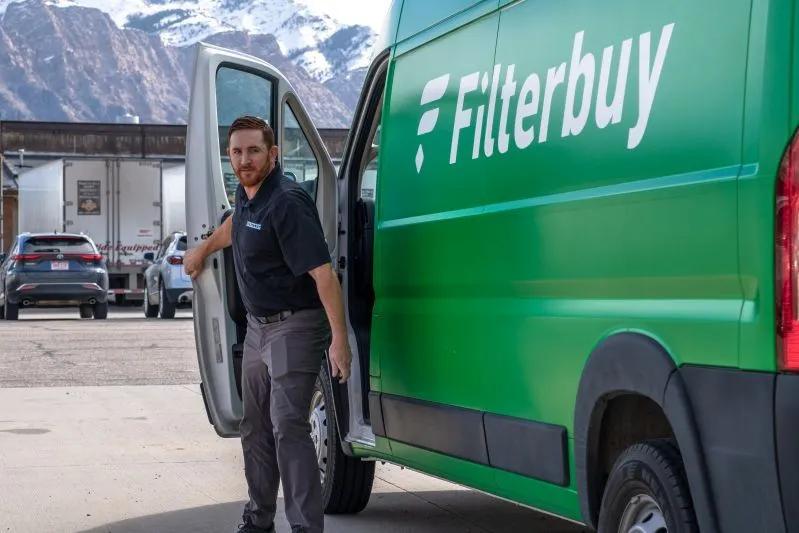 Peut‑on laver les filtres d’un purificateur d’air ? — image d’un employé de Filterbuy arrivant pour un service, une fourgonnette verte de la marque en arrière‑plan.